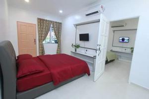 een witte slaapkamer met een rood bed en een televisie bij The Sofea Inn Transit Room Airport Kota Bharu in Pengkalan Cepa