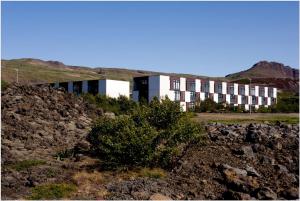 a building on top of a hill with a bush at Bifröst Apartments in Bifrost