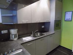 a kitchen with white cabinets and a sink at Akropolis odk in Koksijde