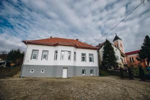 ein weißes Haus mit rotem Dach und einer Kirche in der Unterkunft Mosolyka Vendégház in Zákány