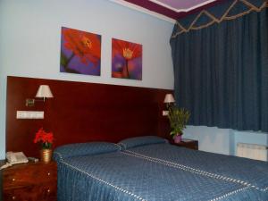 a bedroom with a blue bed and paintings on the wall at Auto Check In Hotel Las Nieves in Jaca