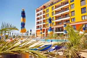 a hotel with a pool and palm trees and umbrellas at Apartment complex Mirage of Nessebar in Nesebar