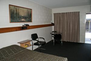 BlackwaterにあるBlack Diamond Motelのベッド、テーブル、椅子が備わるホテルルームです。