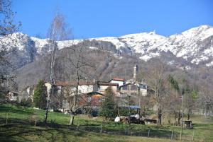 a house in front of a snow covered mountain at A Cà balade in Design in Miglieglia