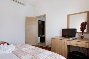 Schlafzimmer mit einem Bett und einem Schreibtisch mit einem TV in der Unterkunft Apartments & Rooms Villa Maslina in Trogir