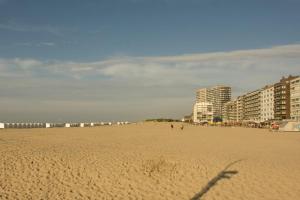 a sandy beach with buildings and people walking on it at Akropolis odk in Koksijde +2 photos