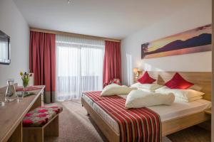 a hotel room with a bed with red curtains at Hotel Wildauerhof in Walchsee
