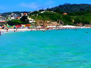 a beach with a bunch of people in the water at Loft Com Vista Para O Mar in Arraial do Cabo