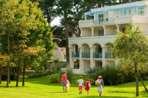 a family walking in the grass in front of a house at Goélia - Résidence Royal Park in La Baule