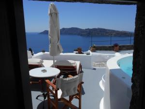 einen Blick vom Balkon eines Hauses mit einem Tisch und einem Sonnenschirm in der Unterkunft Rimida Villas in Oia