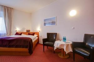 um quarto de hotel com uma cama e duas cadeiras em INA Hotel Consul em Kiel