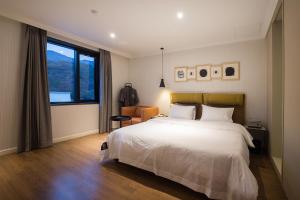 um quarto com uma cama branca e uma grande janela em Brown-Dot Hotel Choeup em Busan