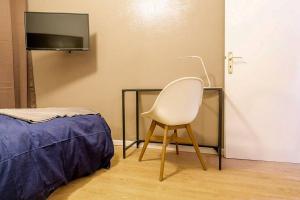 メスにあるStudio Gare Metz Côté Courのベッド1台とテレビ付きの客室内の白い椅子