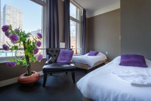 una camera d'albergo con due letti, una sedia e una finestra di Hotel Santa Maria a Rotterdam