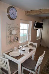 Skruzdynės Apartamentai في نيدا: غرفة طعام مع طاولة وساعة على الحائط