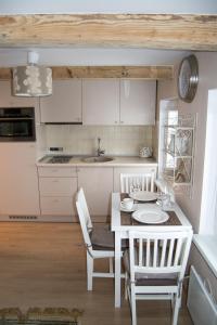 una cocina con mesa y sillas y una cocina con armarios blancos. en Skruzdynės Apartamentai, en Nida