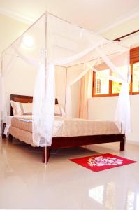 a bedroom with a canopy bed with a red rug at The Palms Beach Hotel in Entebbe