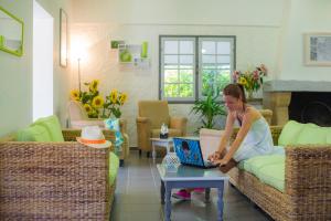 Eine Frau, die mit einem Laptop auf einer Couch sitzt. in der Unterkunft Les Maisons du Golf d'Armagnac in Eauze