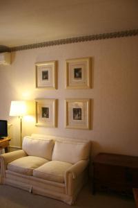 uma sala de estar com um sofá branco e quadros na parede em La Posada de Don Mariano em Pedraza-Segovia