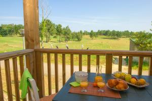 einen Tisch mit Obst und Orangensaft auf dem Balkon in der Unterkunft Les Maisons du Golf d'Armagnac in Eauze