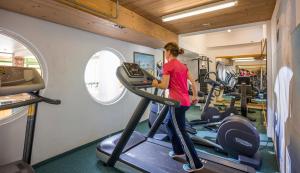 a woman on a treadmill in a gym at Hotel Wildauerhof in Walchsee