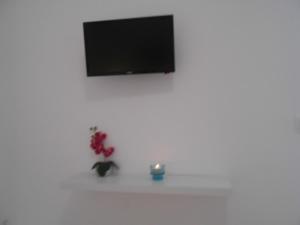 a white shelf with a television on a white wall at Angeliki Pension in Katapola