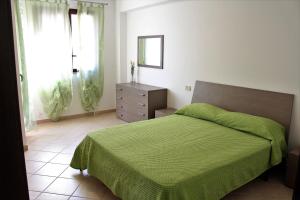 a bedroom with a green bed and a dresser and window at Case Vacanze Orlando Trappeto Summer in Trappeto