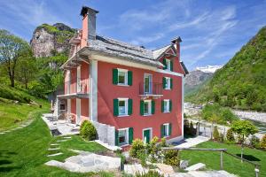 una casa en una colina con montañas en el fondo en MyVerzasca Resort Casa Rossa en Brione