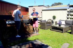 dos hombres parados en un patio sosteniendo un plato de comida en Motel Marengo en Apollo Bay