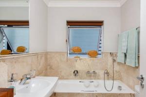 a bathroom with a tub and a sink and two windows at WATERFRONT - Quay Largo two bedroom on the water with mooring in Knysna +4 photos