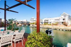 a patio with a table and chairs next to a river at WATERFRONT - Quay Largo two bedroom on the water with mooring in Knysna
