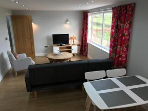 a living room with a black couch and a table at The Cothi Bridge Apartments in Carmarthen