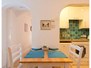 a dining room with a table and a kitchen at Sand Martin in Looe