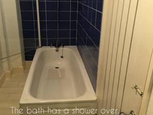 a bath tub in a bathroom with blue tiles at Sand Martin in Looe