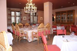 a dining room with tables and chairs and a chandelier at La Posada de Don Mariano in Pedraza-Segovia