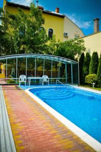 una piscina con 2 sillas junto a una casa en BL Luxus Apartman, en Szeged