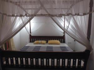 a bedroom with a canopy bed with two pillows at Lanrich Eco Villas in Mirissa