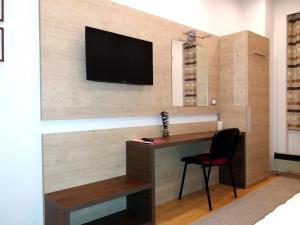 a room with a desk and a television on a wall at Apartment Millas in Niš