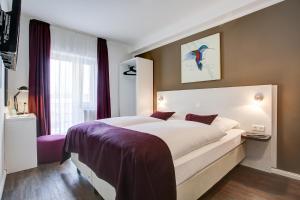 a bedroom with a large white bed with purple sheets at Hotel West in Hamburg