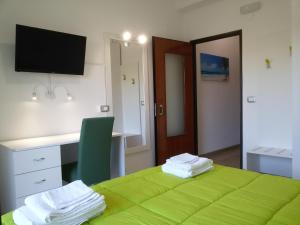 ソヴェラート・マリーナにあるHotel Elizabeth - Soveratoの緑のベッド、デスク、コンピュータが備わる客室です。