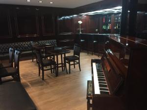 a bar with tables and chairs and a piano at Duomo Park Hotel in Curitiba