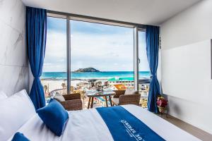 a bedroom with a bed and a view of the beach at Blue Spring Hotel in Jeju