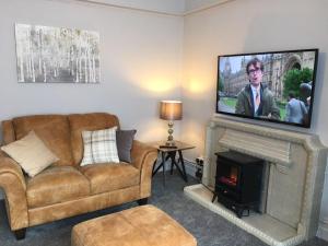 a living room with a couch and a television over a fireplace at @33 Fab Townhouse in Holyhead
