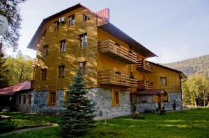 a large wooden house with a tree in front of it at Три Брати in Grebenov