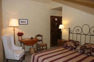 a bedroom with a bed and a chair and a table at La Posada de Don Mariano in Pedraza-Segovia