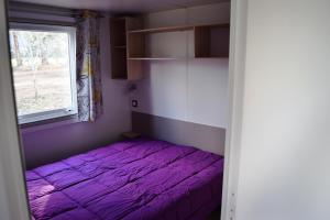 een paars bed in een kamer met een raam bij Camping Paradella in Calenzana