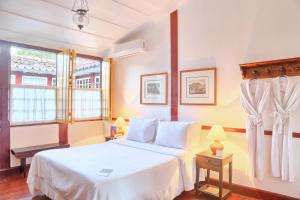 1 dormitorio con cama blanca y ventana en Pousada do Ouro, en Paraty