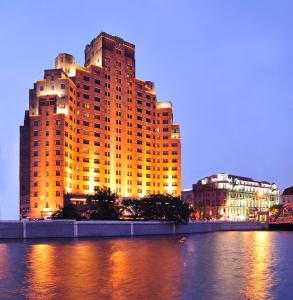 un gran edificio amarillo junto a un río con edificios en Broadway Mansions Hotel - Bund, en Shanghái