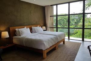 a bedroom with a large bed with white pillows at Inchantreedoopool in Kanchanaburi City