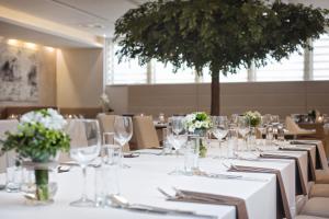 a dining room with white tables and chairs and a tree at Hotel Petropol in Płock